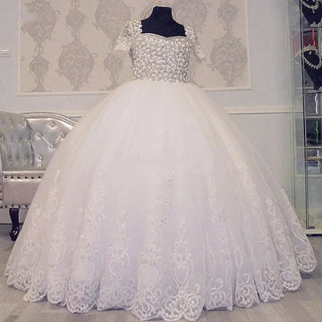 Elegante vestido de fiesta blanco con encaje bordado, corpiño de cuentas y mangas cortas para eventos formales.