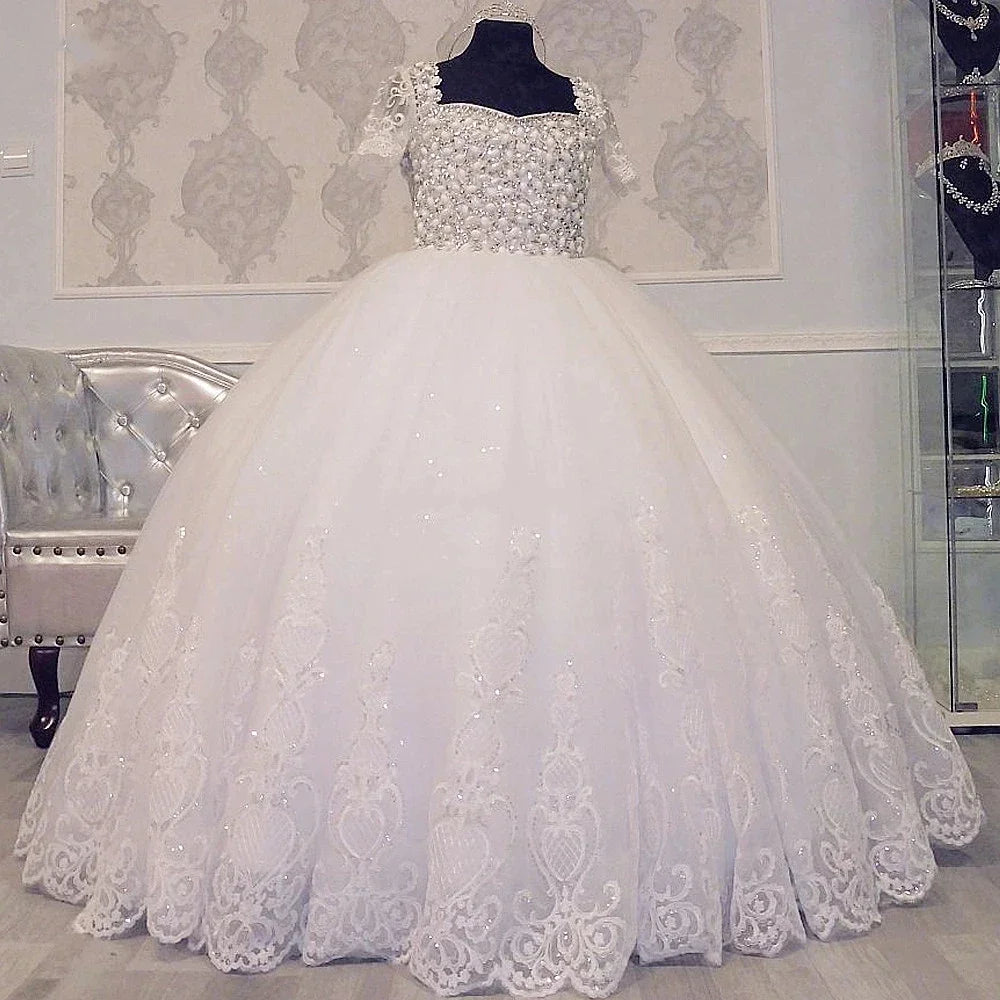 Elegante vestido de fiesta blanco con encaje bordado, corpiño de cuentas y mangas cortas para eventos formales.